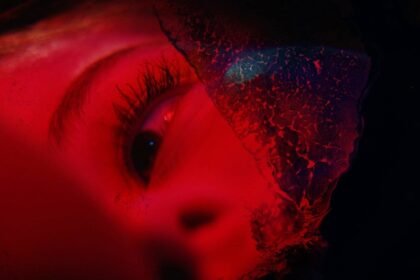 An image of a woman's eye, illuminated in red, looking sadly at something off camera