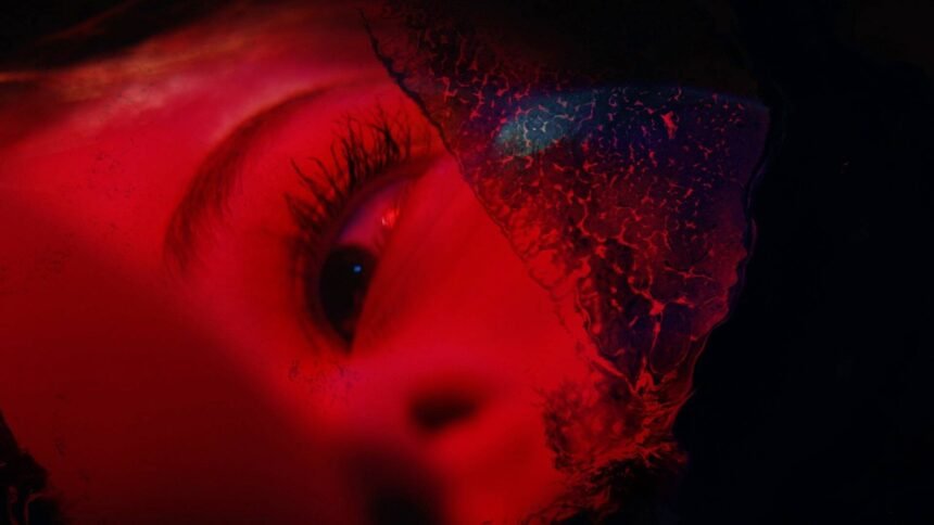 An image of a woman's eye, illuminated in red, looking sadly at something off camera