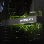 Closeup of a dark grey graphics card with white 'GeForce RTX' backlighting within a PC build